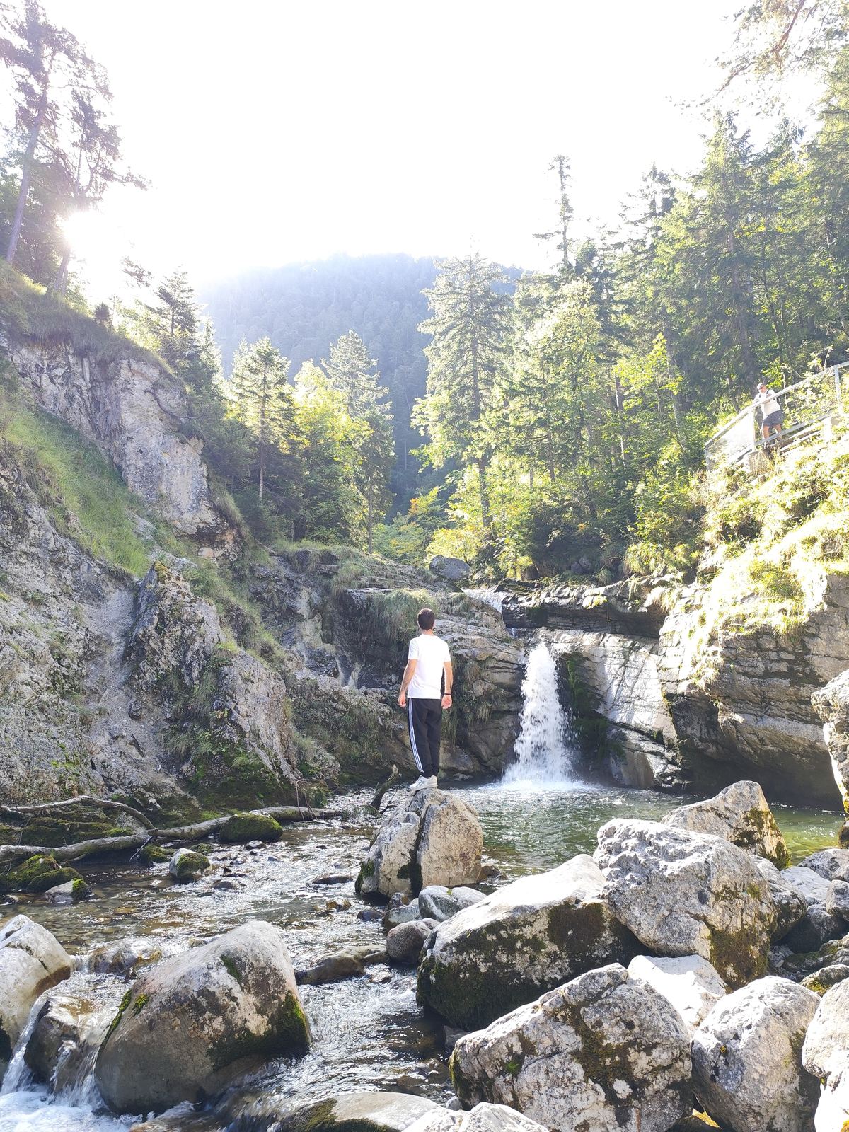 Idlir Sulstarova standing on a rock by a waterfall in a mountain gorge